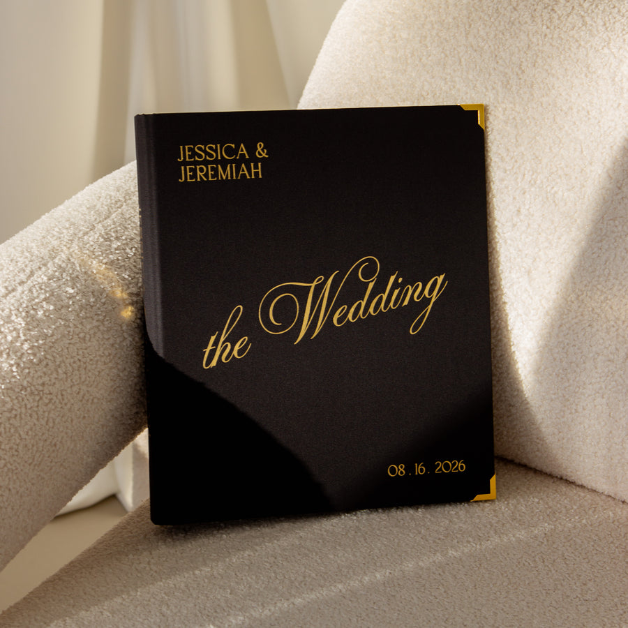 Black wedding album with gold text on a textured surface